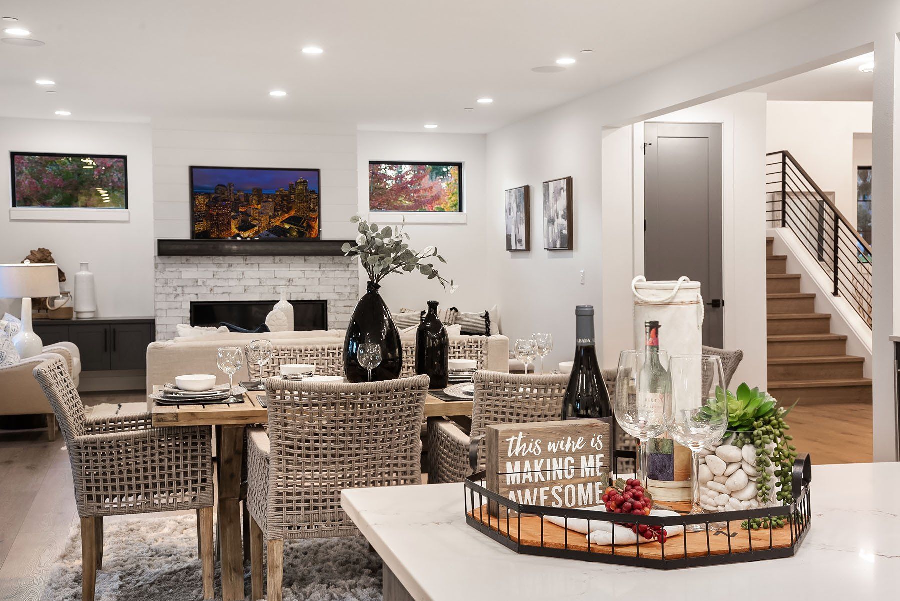 Dining area with bar stools, table settings, and a living room with a fireplace and staircase.
