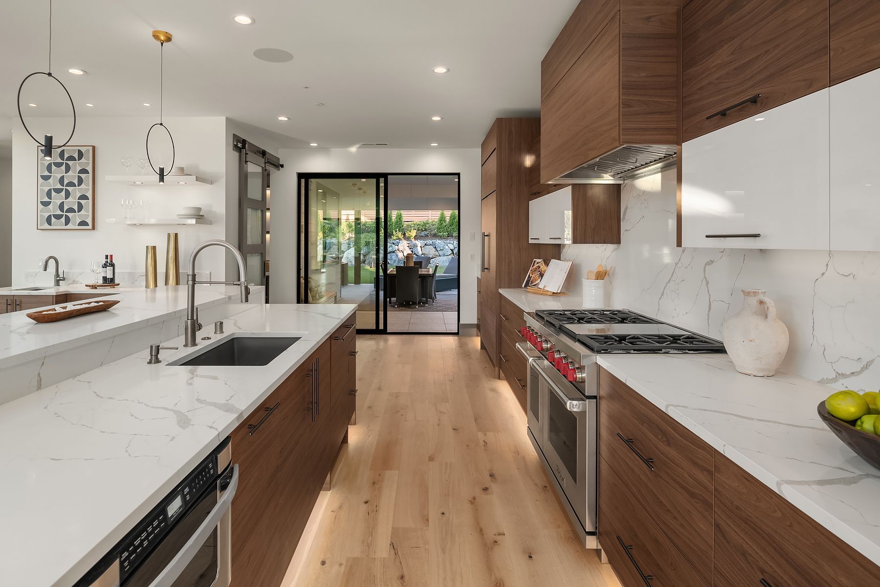 Modern kitchen with wood cabinets, white countertops, stainless steel appliances, and a view to the patio.