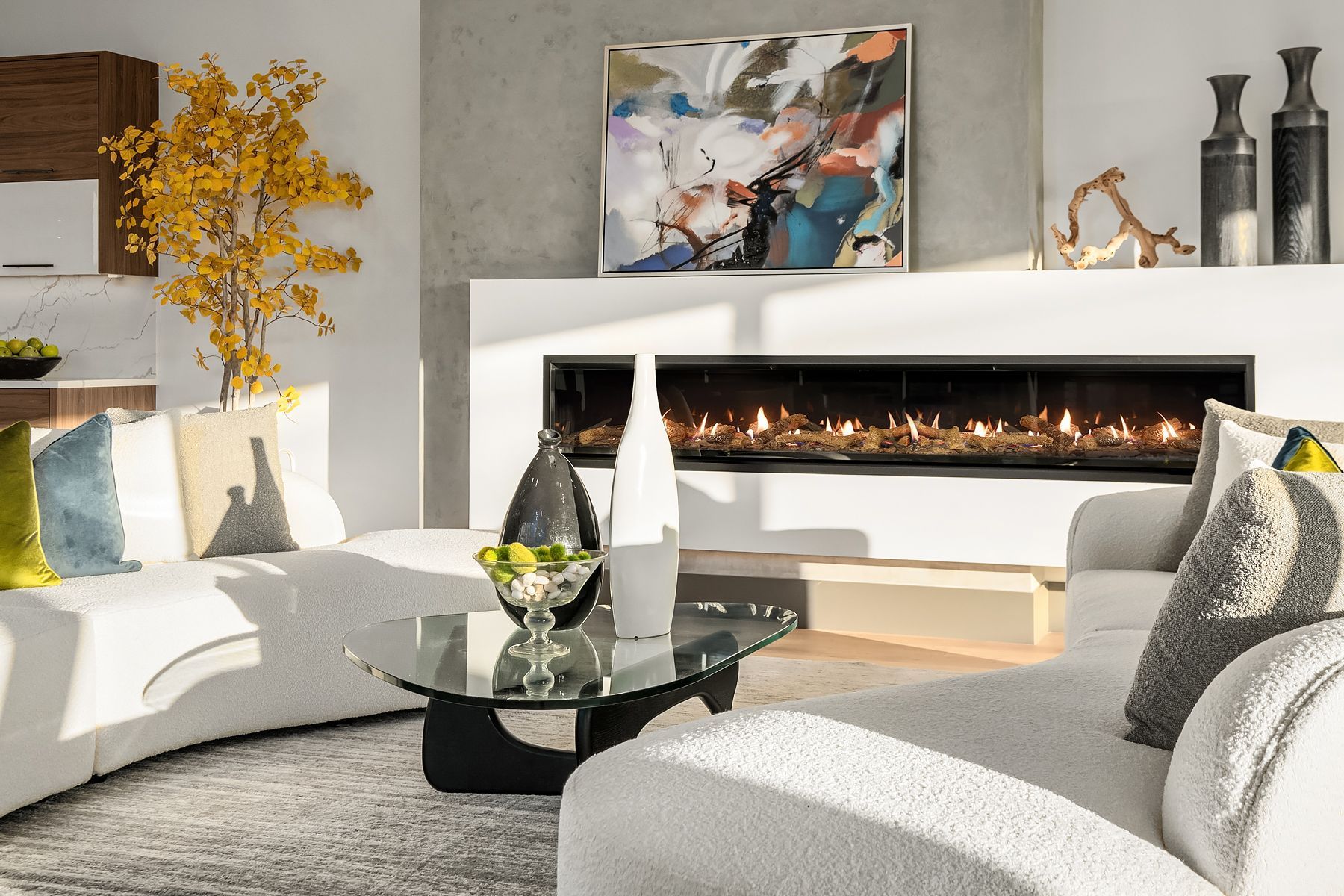 Modern living room with fireplace, white couch, colorful art, and decorative items.