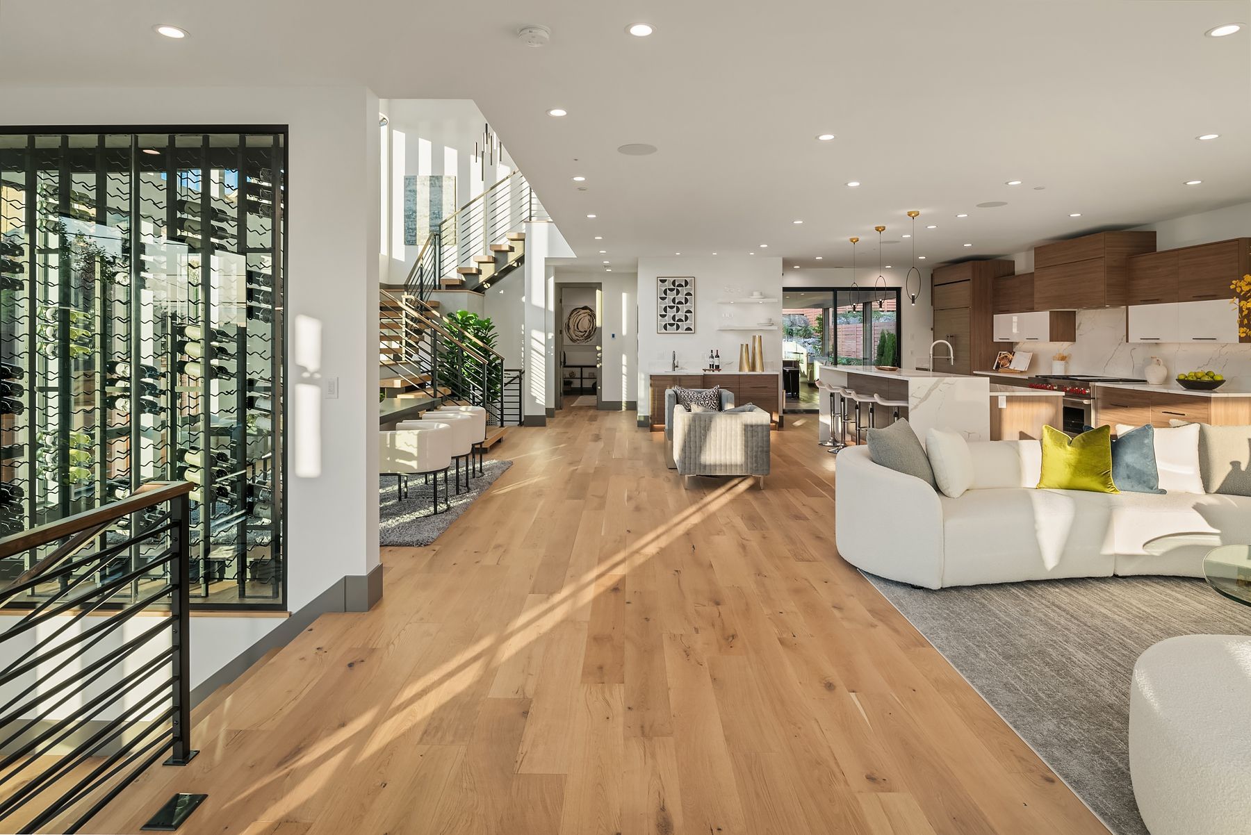 Spacious, modern living room with hardwood floors, white walls, and a large glass window.