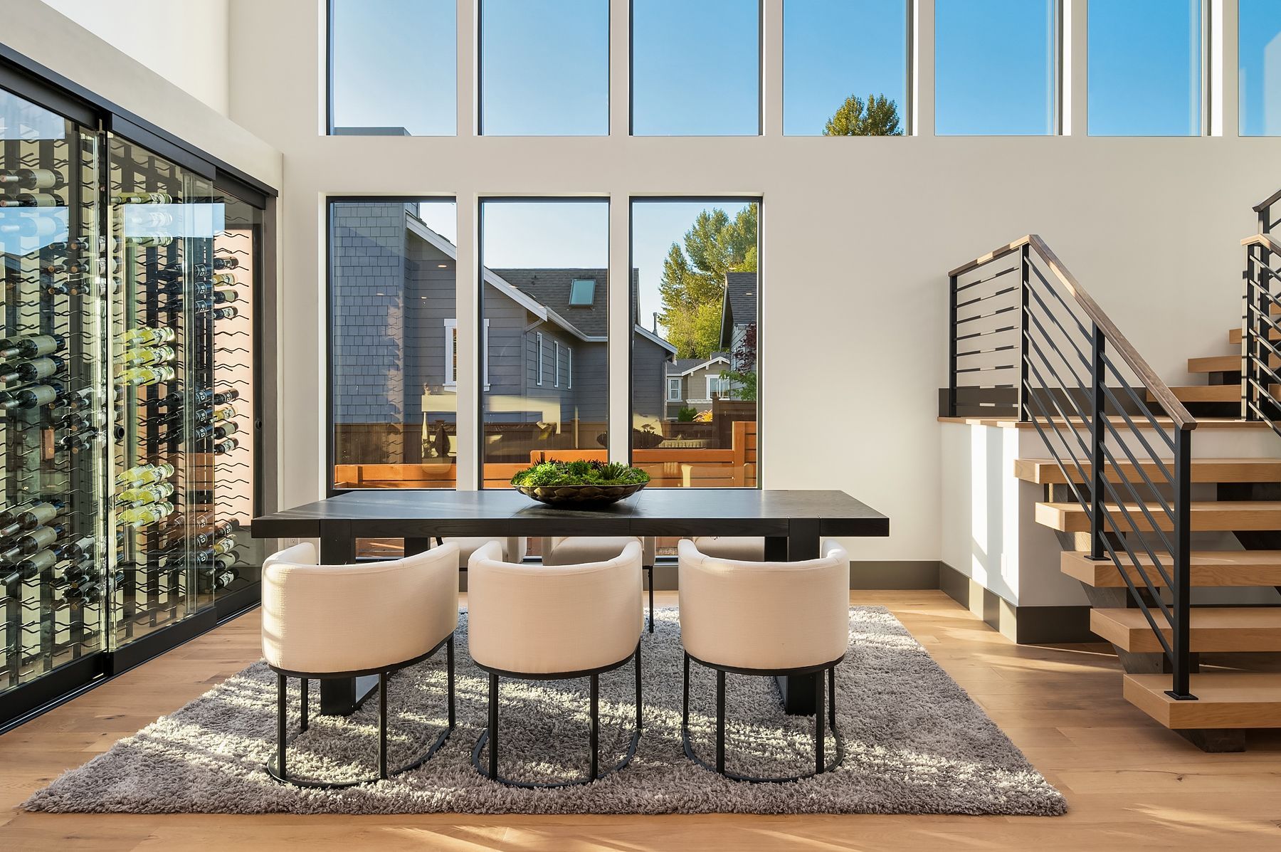 Dining room with table, chairs, and wine cellar, with window overlooking neighborhood.