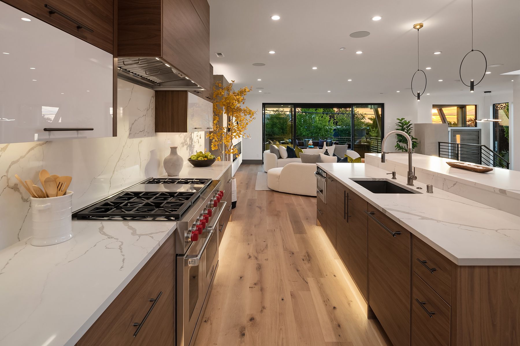 Modern kitchen with wood cabinets, white countertops, and stainless steel appliances. Sliding glass doors lead to a patio.