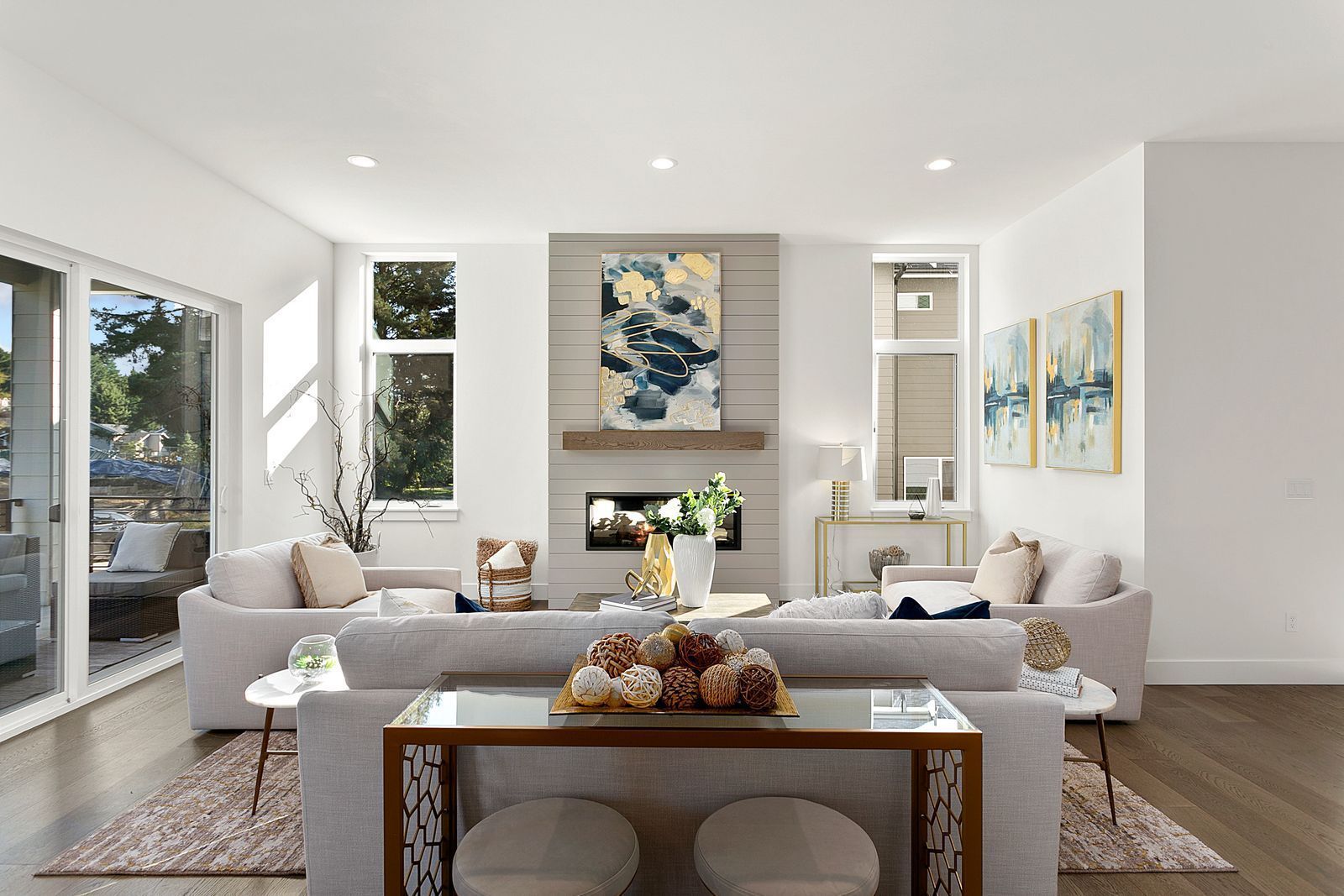 Bright, modern living room with fireplace, large couch, and artwork. White walls and hardwood floors.