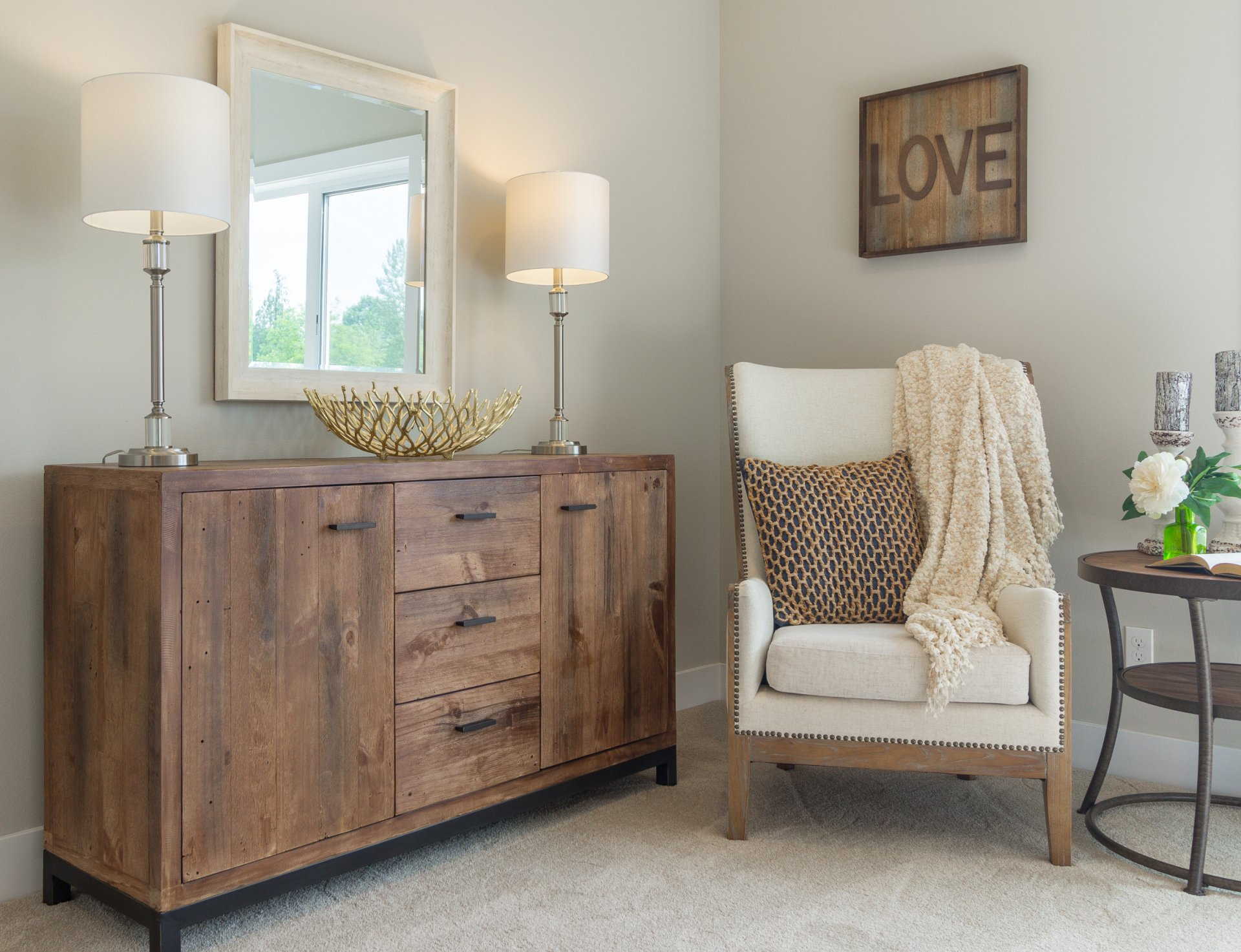 Wooden cabinet with lamps, mirror, chair with throw, small table, and 