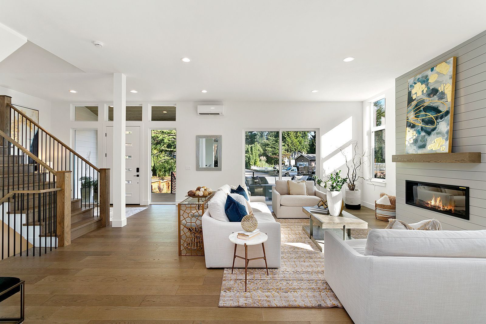 Bright, open living room with white walls, wood floors, and a fireplace.