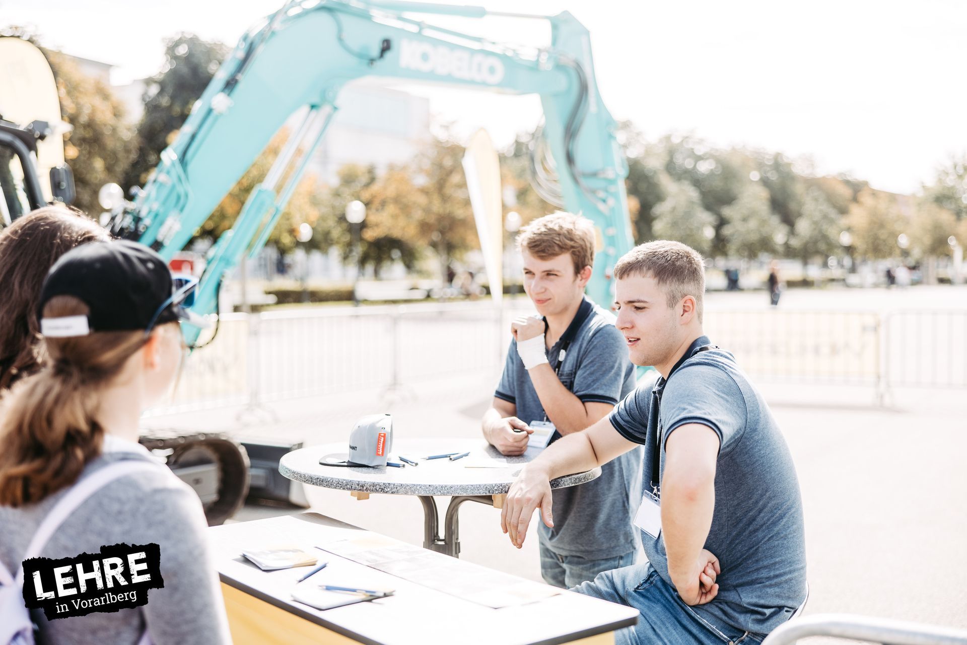 Beratung an Infostand. Bagger im Hintergrund