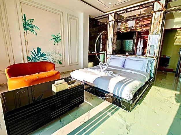 Luxury hotel room with a bed, orange sofa, and black cabinet.