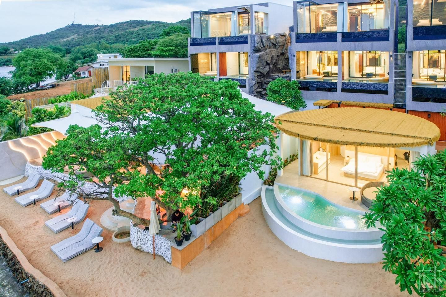 Luxury resort with beach access; buildings with modern design, lounge chairs, and a private pool.