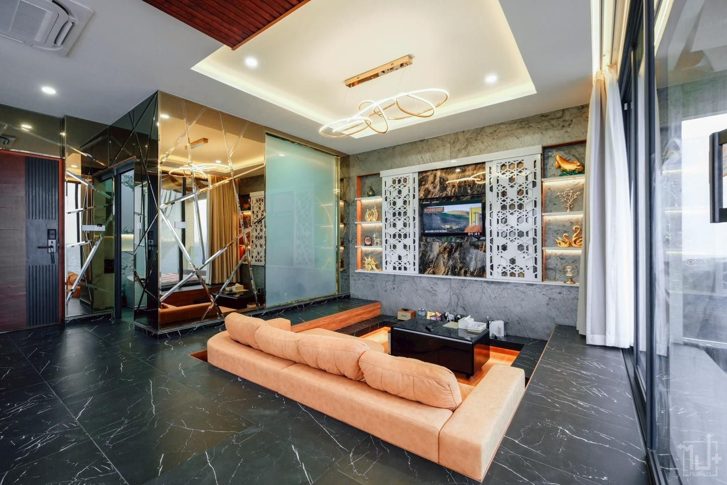 Luxurious living room with tan sofa, black tile floor, mirrored walls, and decorative shelving.