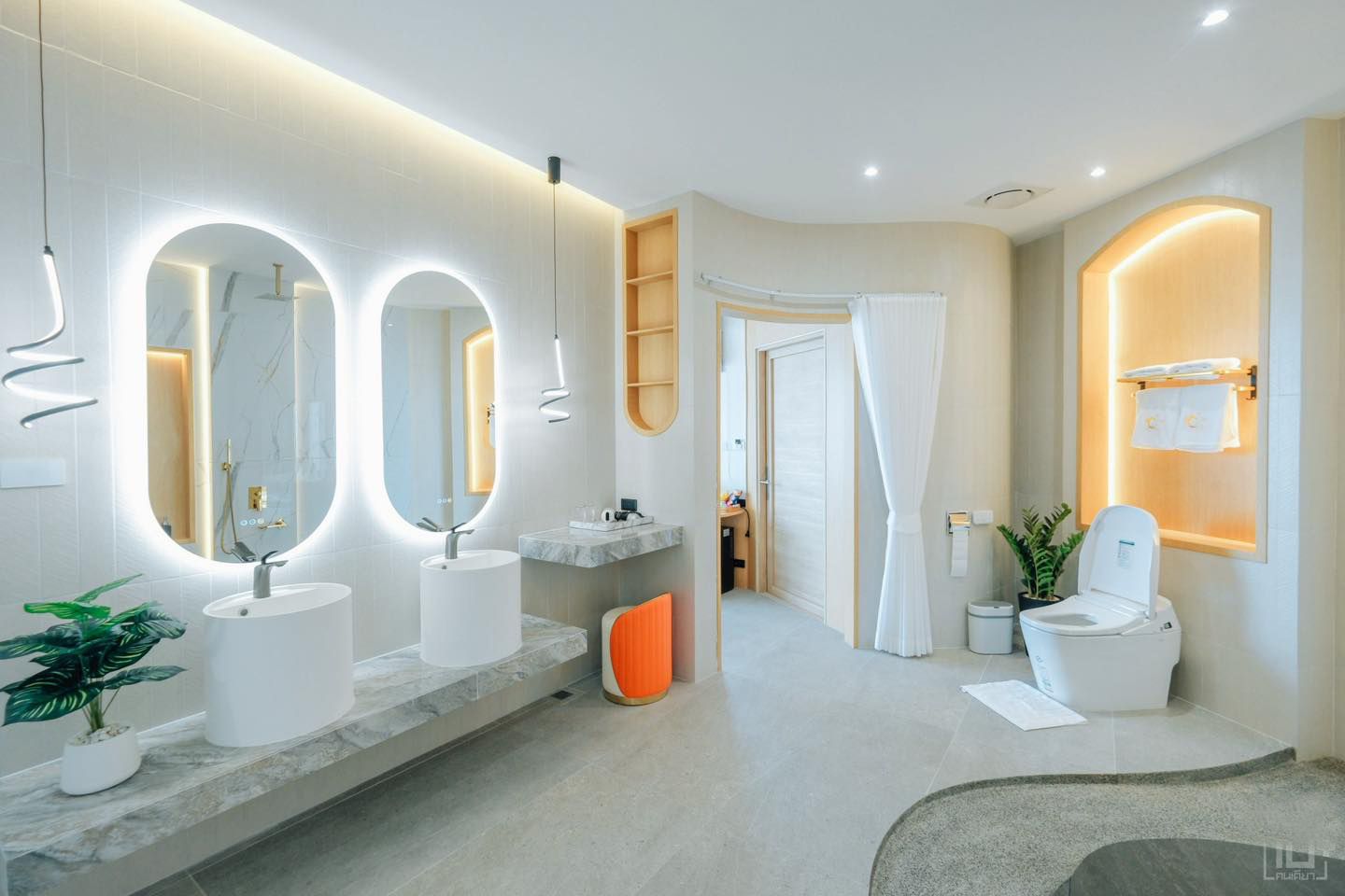 Modern bathroom with two oval backlit mirrors over sinks, white fixtures, and a curved doorway.