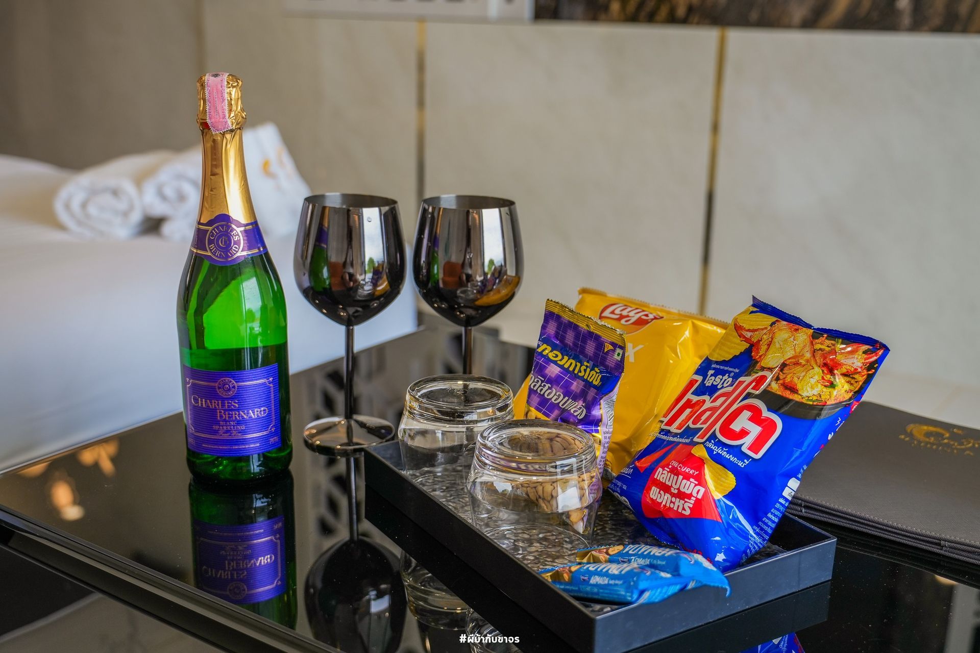 Champagne bottle, wine glasses, and snacks on a tray in a hotel room.