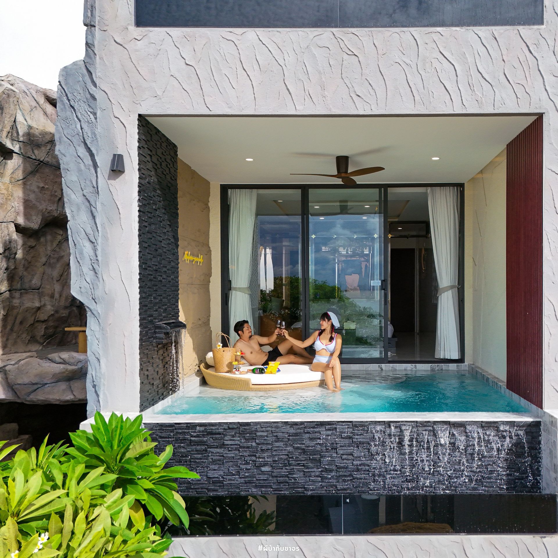 People toasting drinks in a plunge pool outside a modern hotel room.