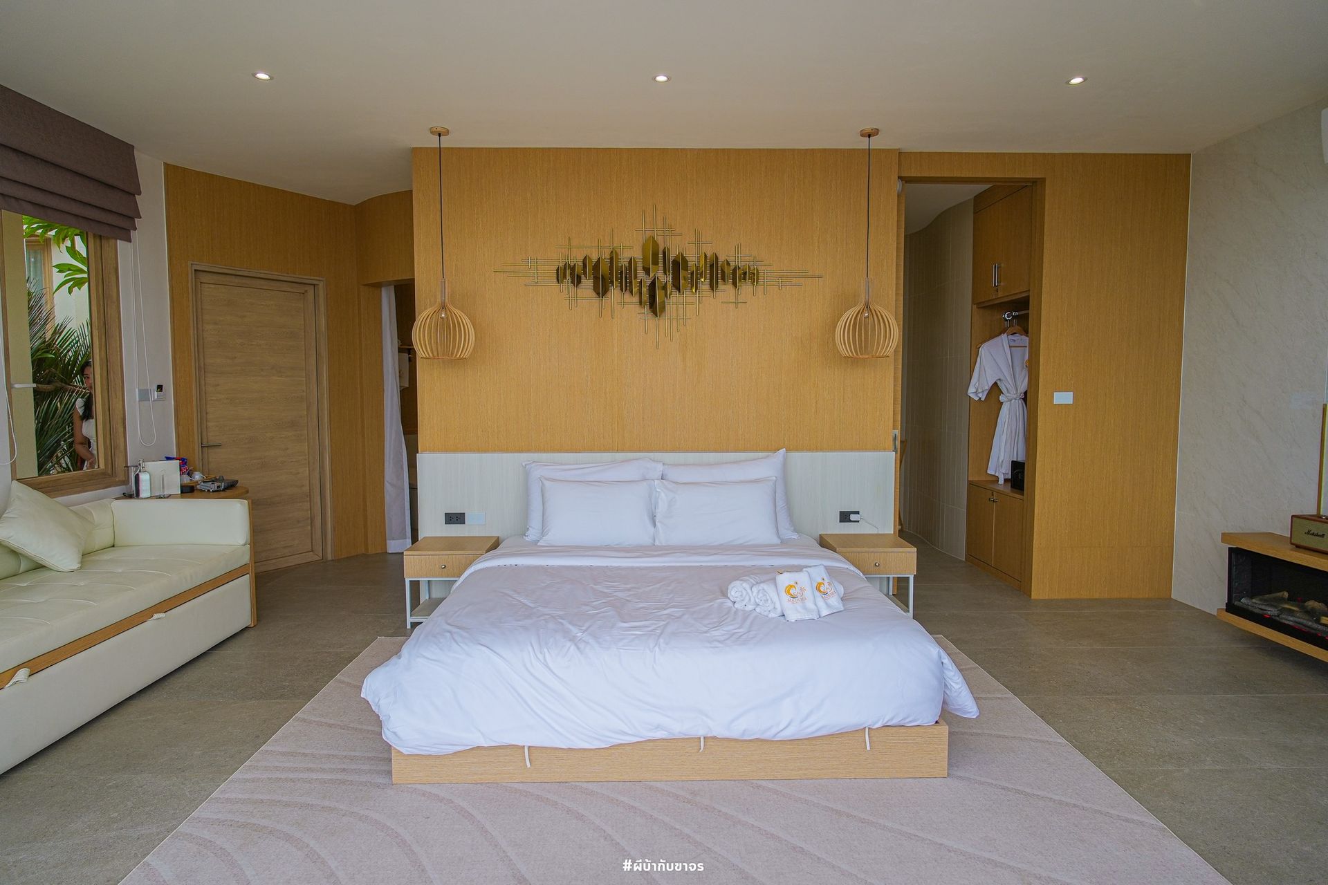 Spacious bedroom with a bed, light wood accents, and a sofa.