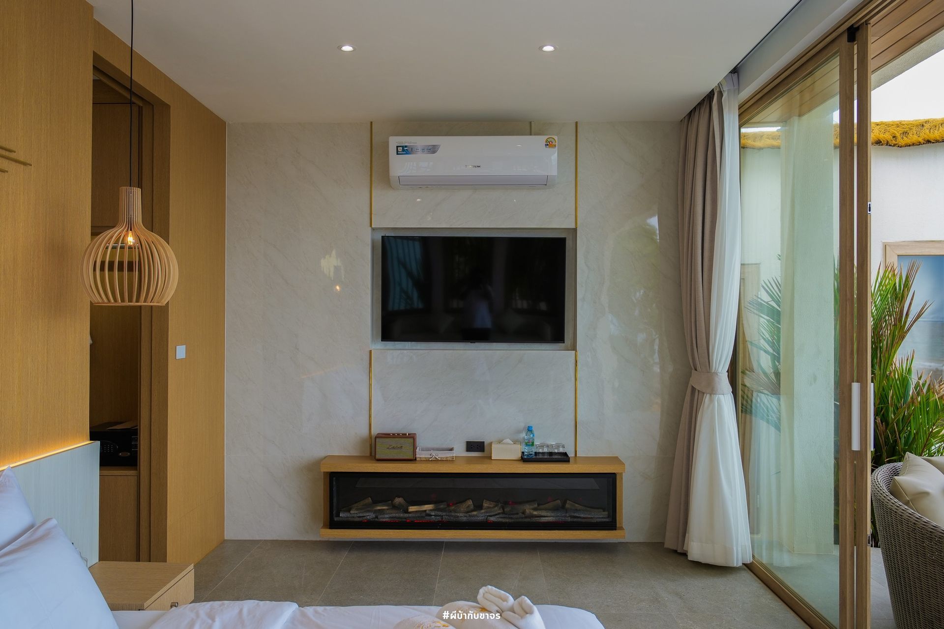 Bedroom with TV on wall, fireplace, sliding glass door to patio. Beige, gold accents.