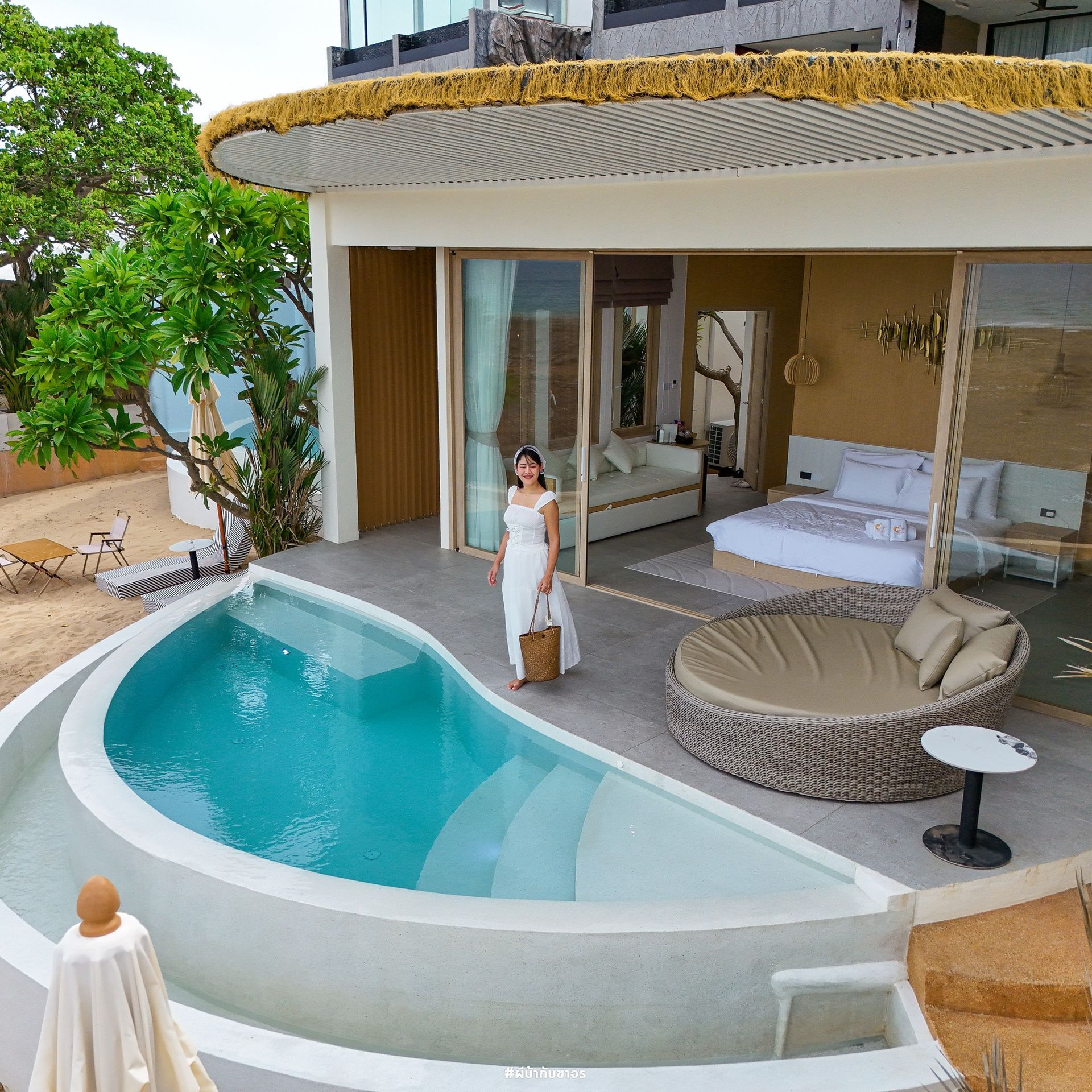 Woman in white dress standing by a private pool, with a bedroom visible through the open doors.