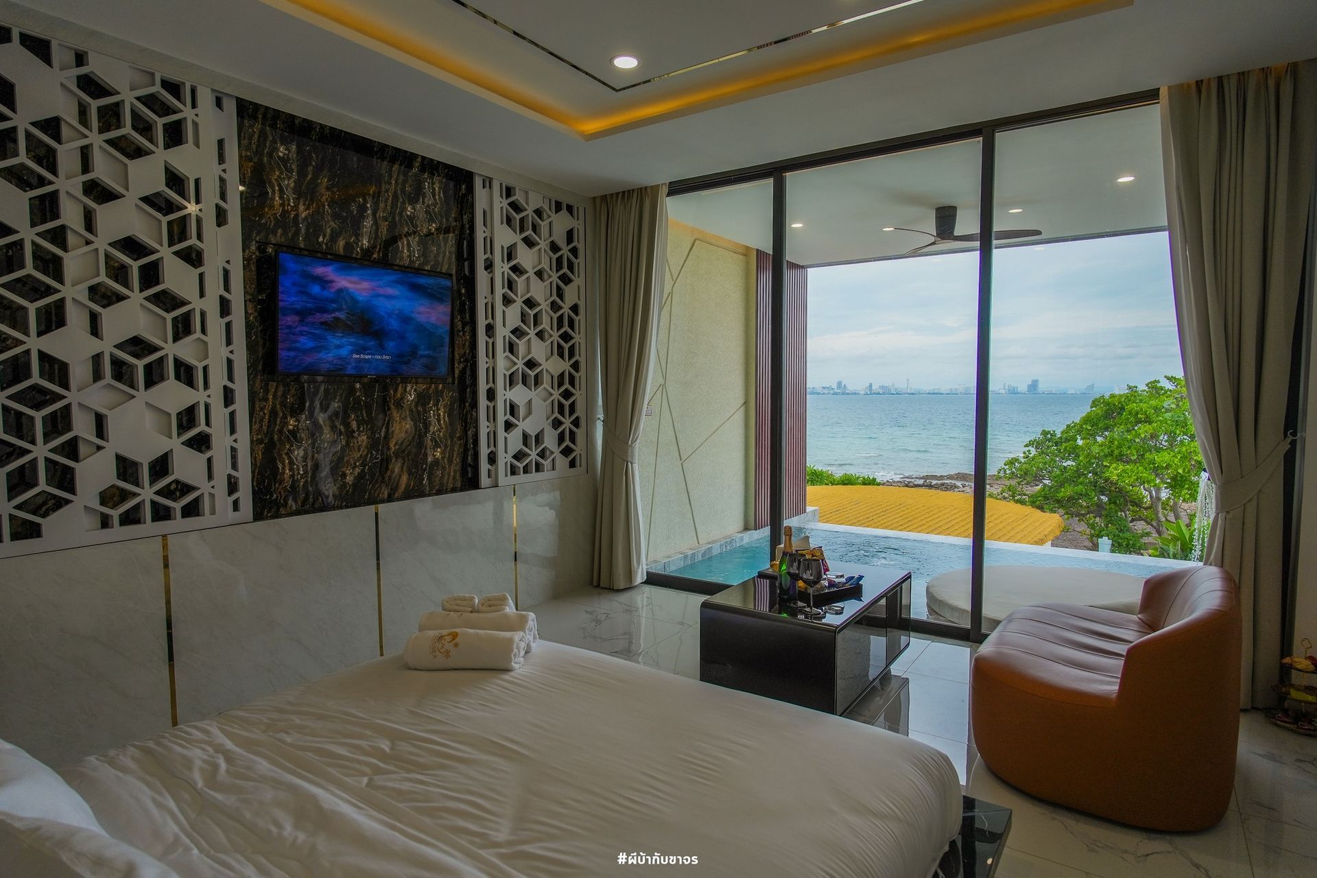 Luxury hotel room with ocean view, modern decor, and a sitting area.