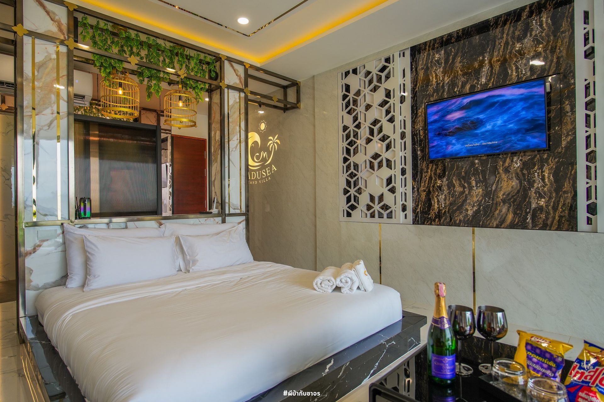 Luxurious hotel room with a bed, TV, and table with champagne.