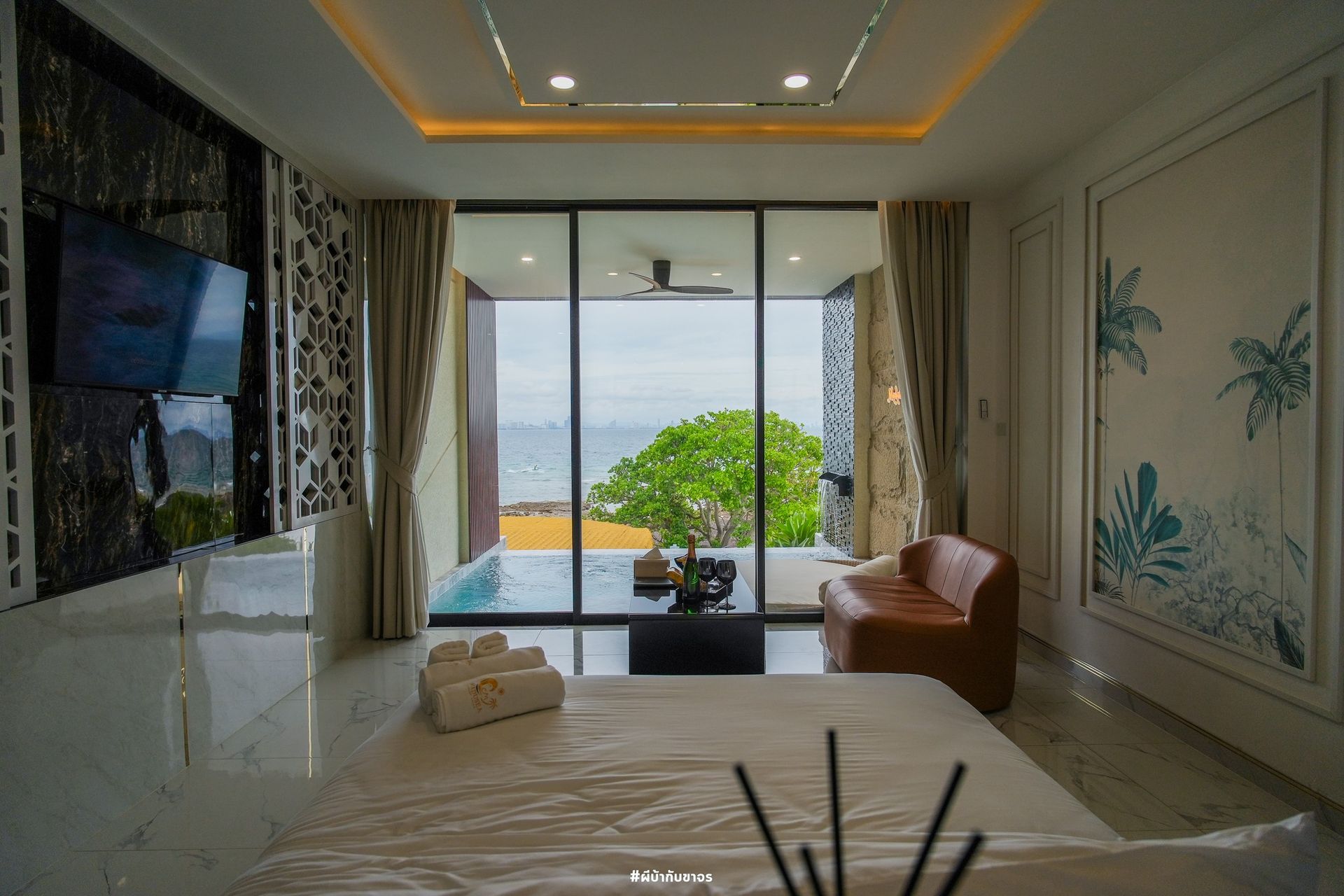 Bedroom with ocean view, private pool, modern decor. Large window, leather sofa, tv on the wall.