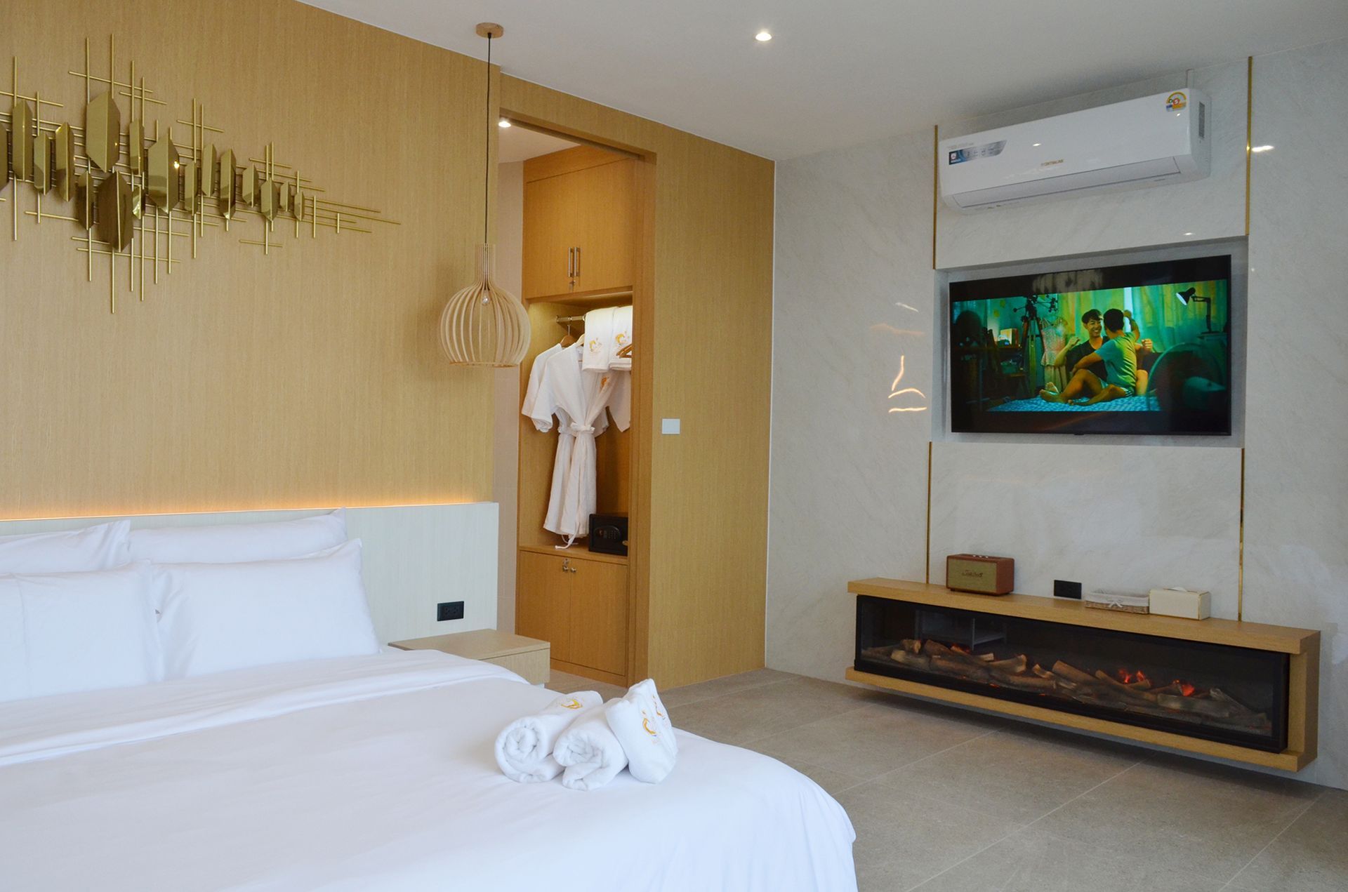 Bedroom with bed, closet, TV, fireplace, and decorative wall art; neutral tones.