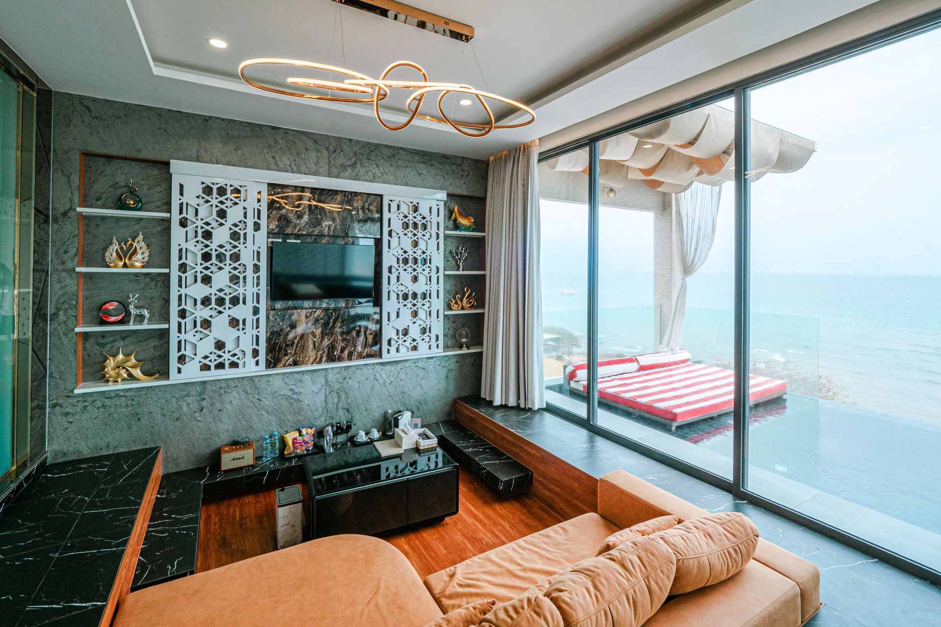 Living room with ocean view, brown couch, TV, and outdoor daybed.