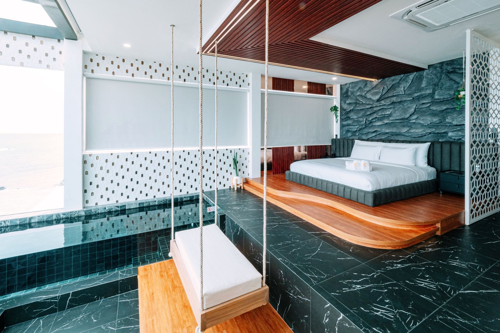 Luxury hotel suite with swing, pool, king-sized bed, and modern decor.
