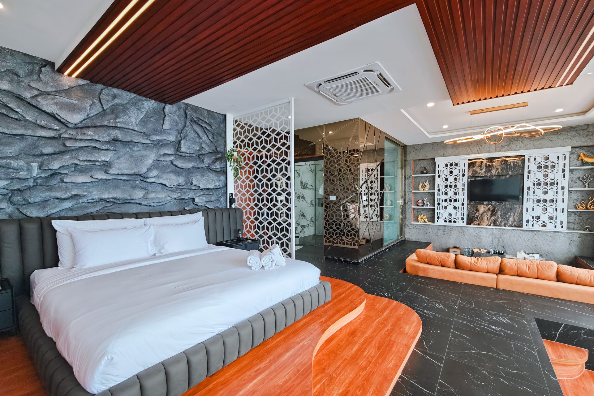 Luxury hotel room with gray stone wall, bed, and orange accents.