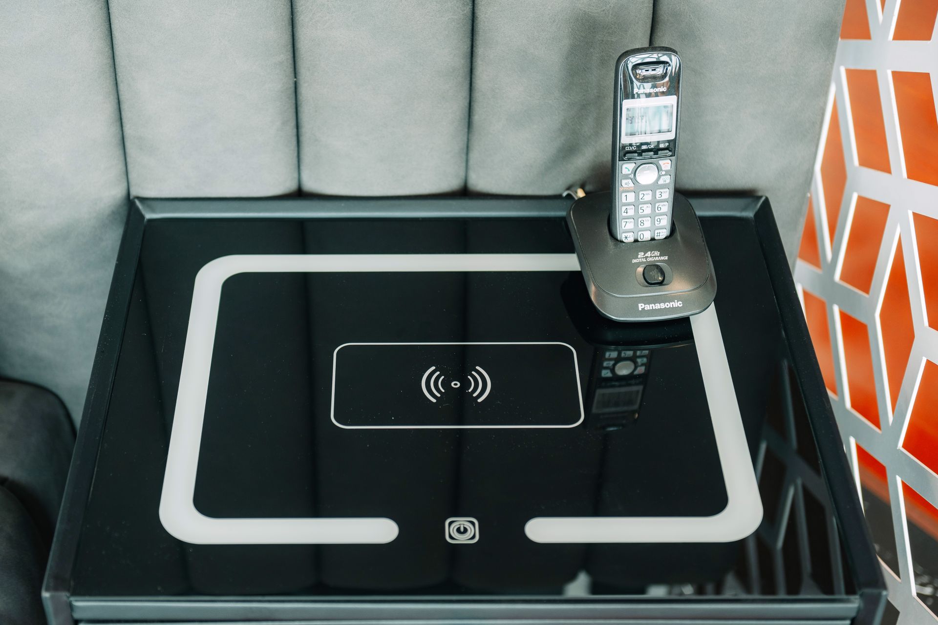 Black side table with a built-in wireless charger and landline phone.