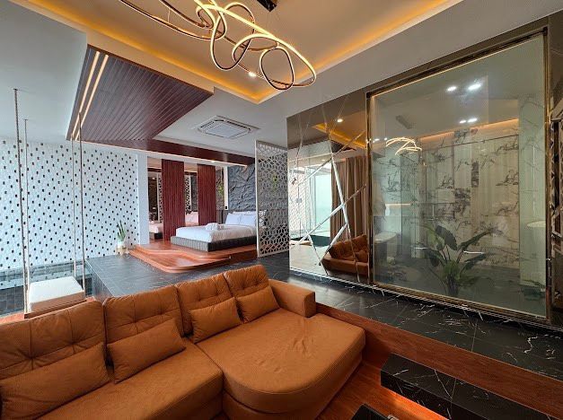 Luxurious bedroom interior with orange sectional, bed, glass wall, and modern lighting.