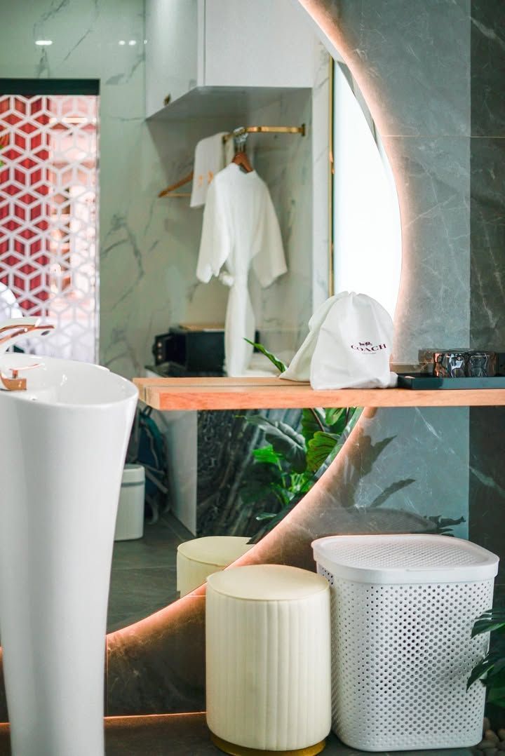 Modern bathroom with marble walls, a curved mirror, and a white sink.