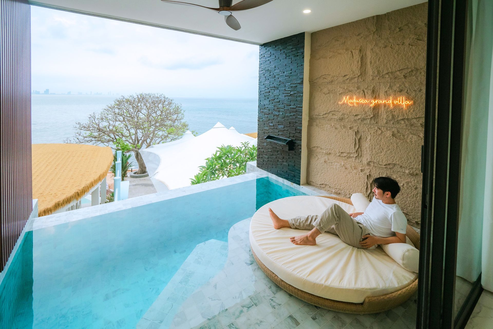 Person relaxing on a round daybed in a pool overlooking the ocean.