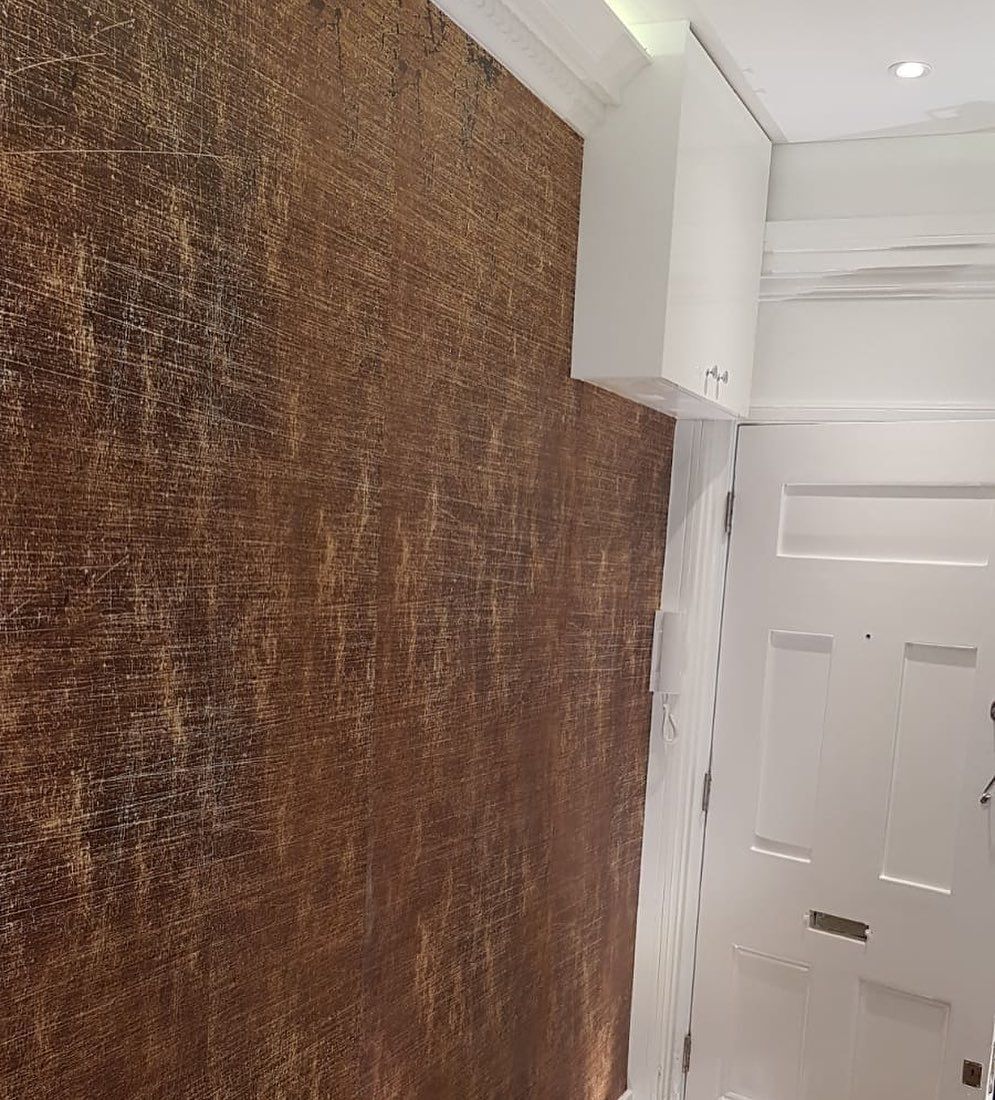 Brown textured wall beside a white door with white trim and a small white cabinet.