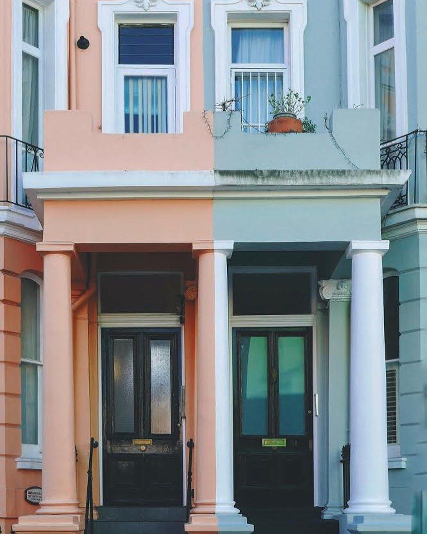 Row of colorful Victorian houses: peach and teal paint, white pillars, dark doors.