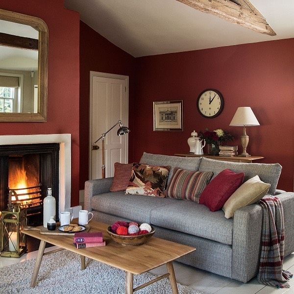 Cozy living room with a red wall, gray sofa, fireplace, and wooden coffee table with a bowl of yarn.