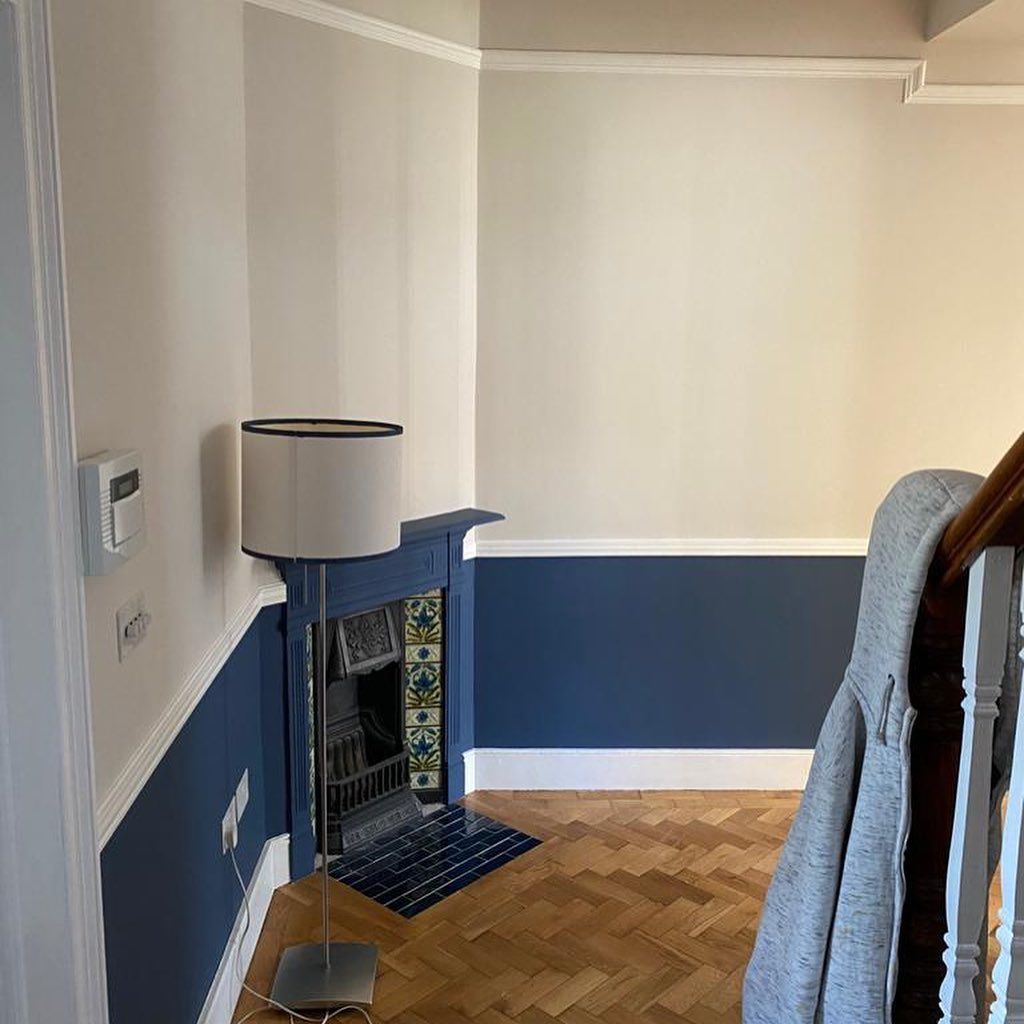 Hallway with blue and white walls, a decorative fireplace, and herringbone wood floor.