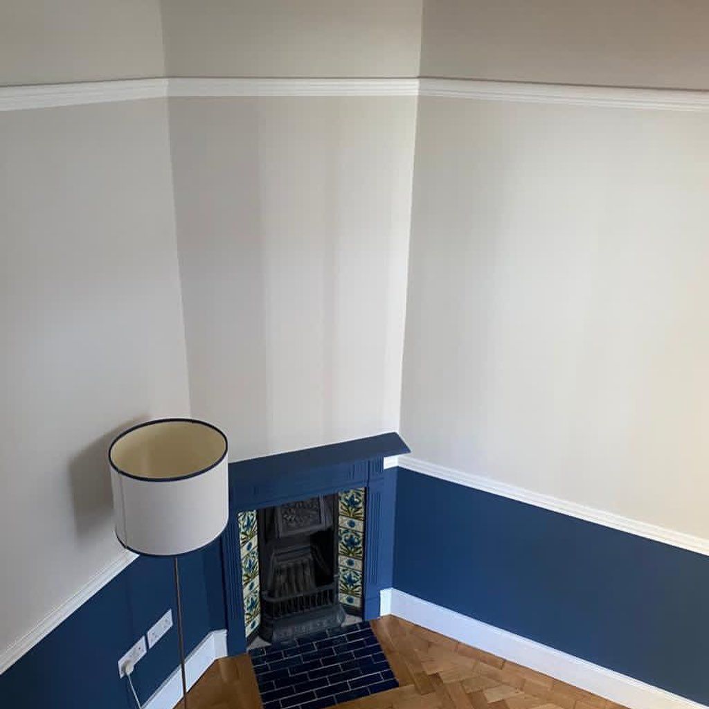 Room with blue and gray walls, fireplace, floor lamp, and hardwood floor.