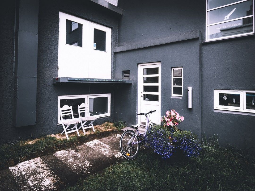 Gray building exterior with white door, windows, and bicycle with flowers.