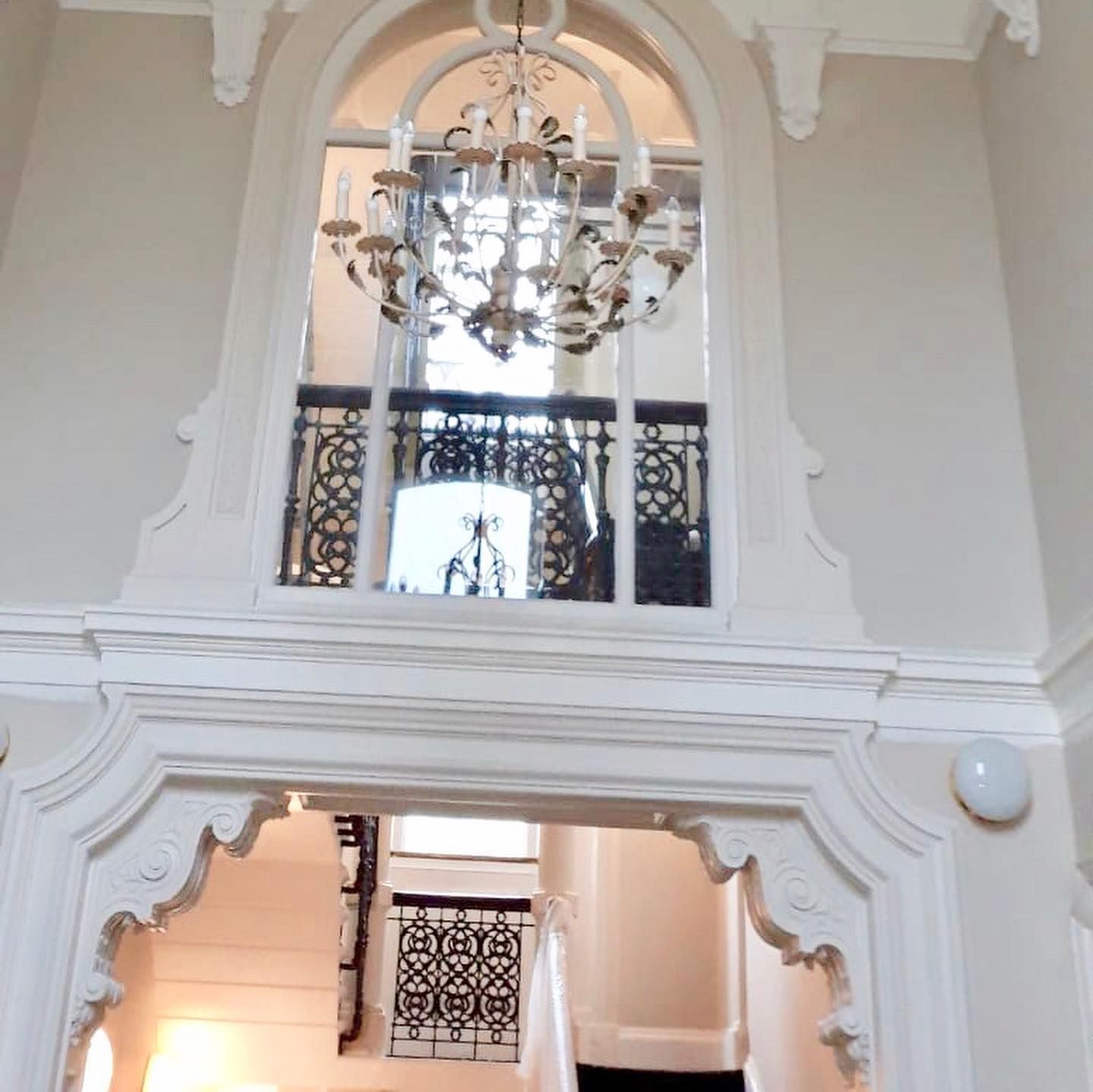 Ornate entryway with chandelier, architectural details, and a staircase.