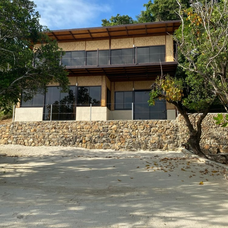 A large house sits on top of a rocky hillside