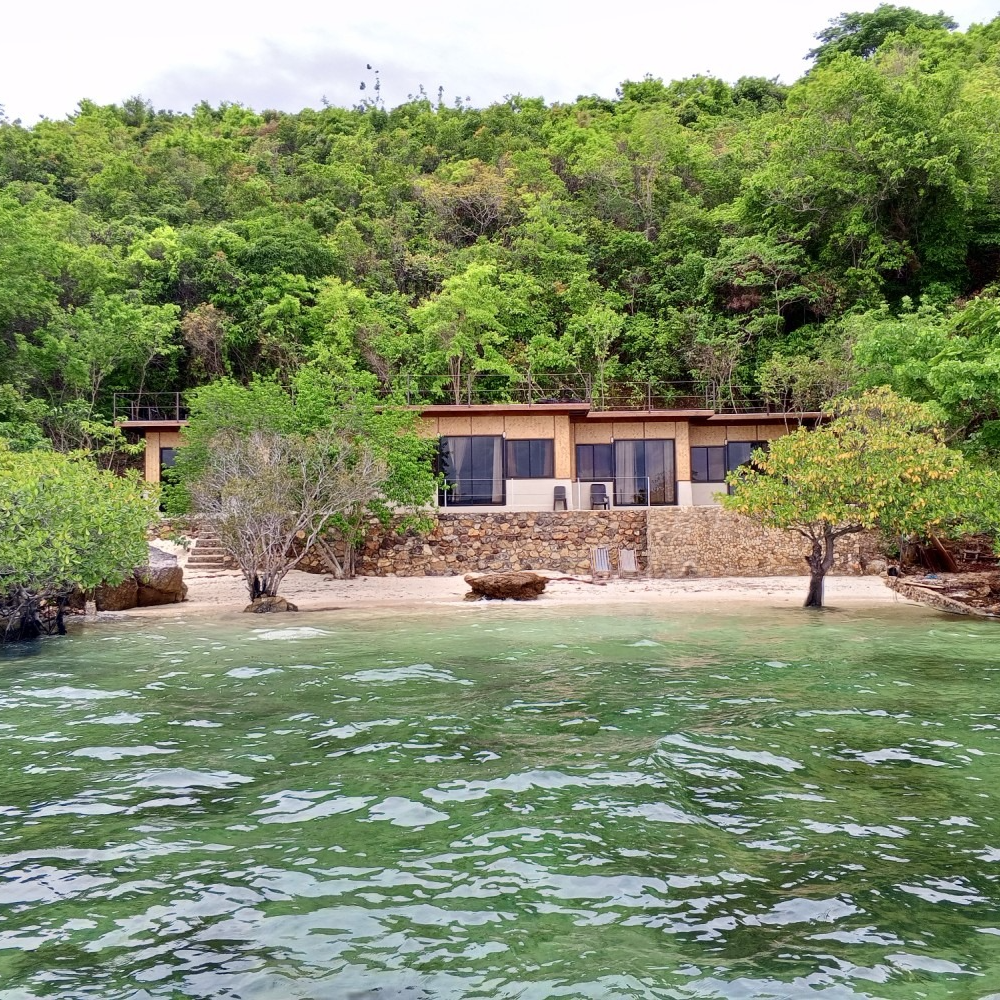 A house sits on a small island in the middle of the ocean
