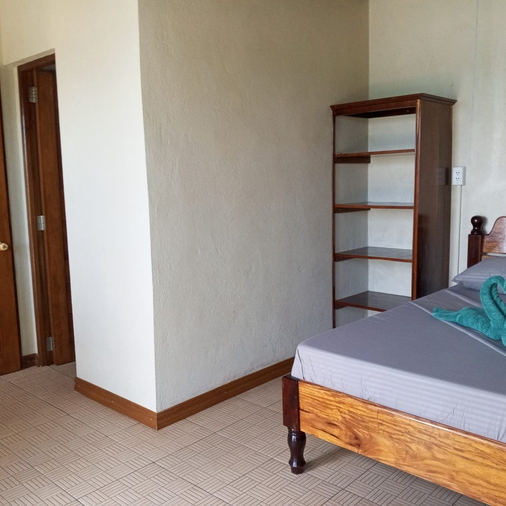 A bedroom with a bed , shelf , and door.