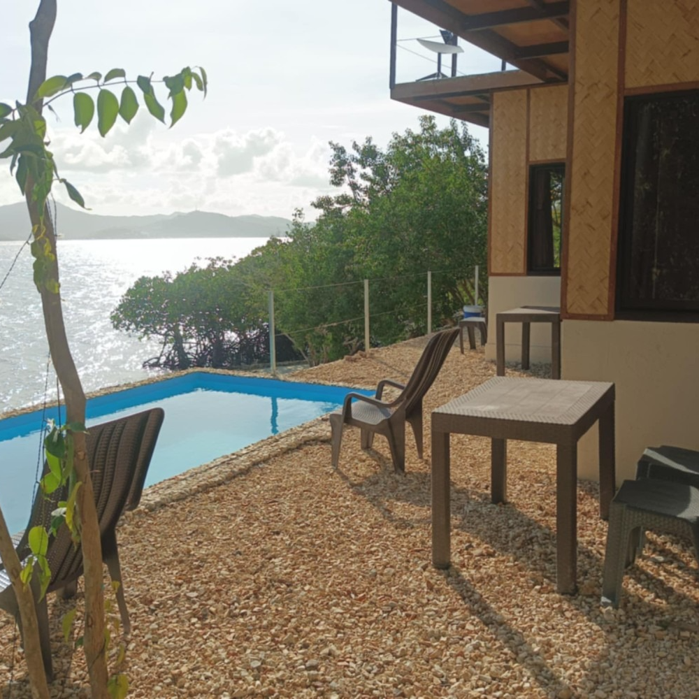 A swimming pool with chairs and tables next to it