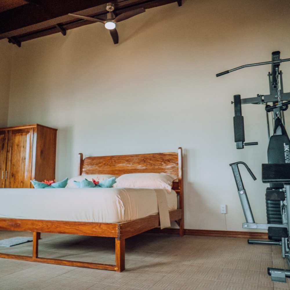 A bedroom with a bed and a gym equipment