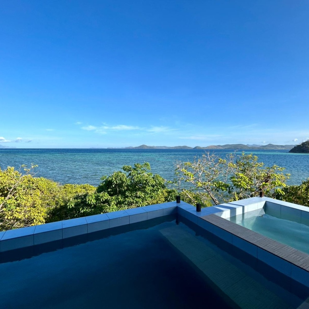 A swimming pool with a view of the ocean on a sunny day.