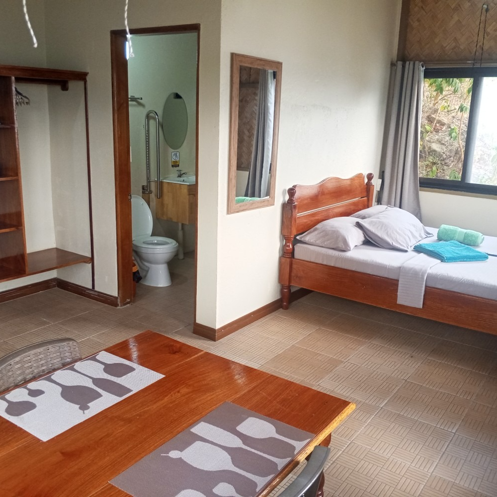 A bedroom with a bed a table and a toilet