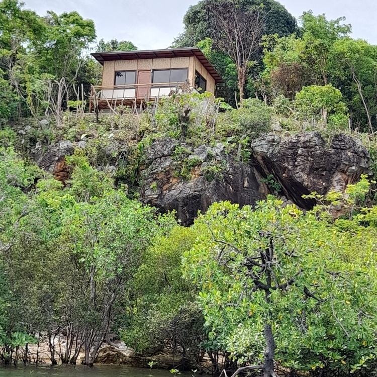 A small house is sitting on top of a rocky hill surrounded by trees.