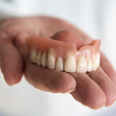 Hand Holding Dentures — Central Coast Denture Clinic In Erina, NSW
