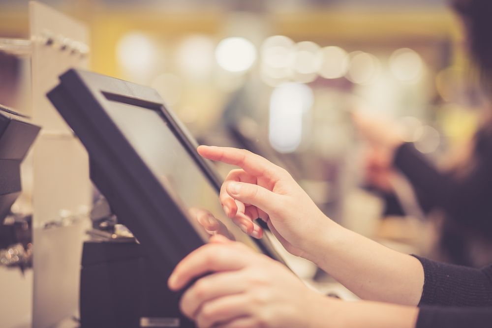 A Woman Is Using A Cash Register In A Store — Coastal Registers & POS In Ruthven, NSW