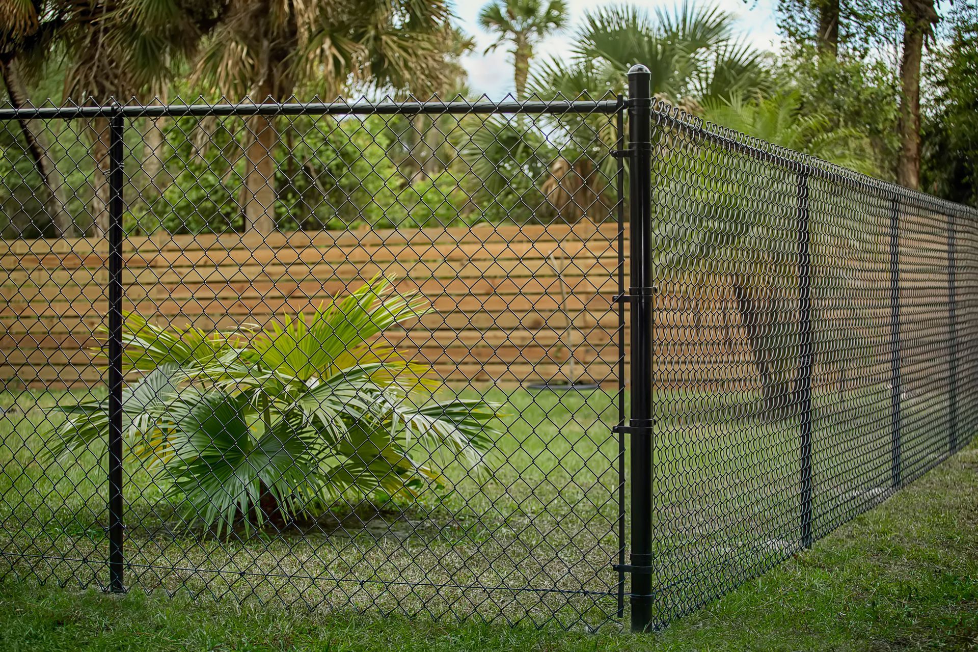 A wooden fence with a gate and trees in the background.