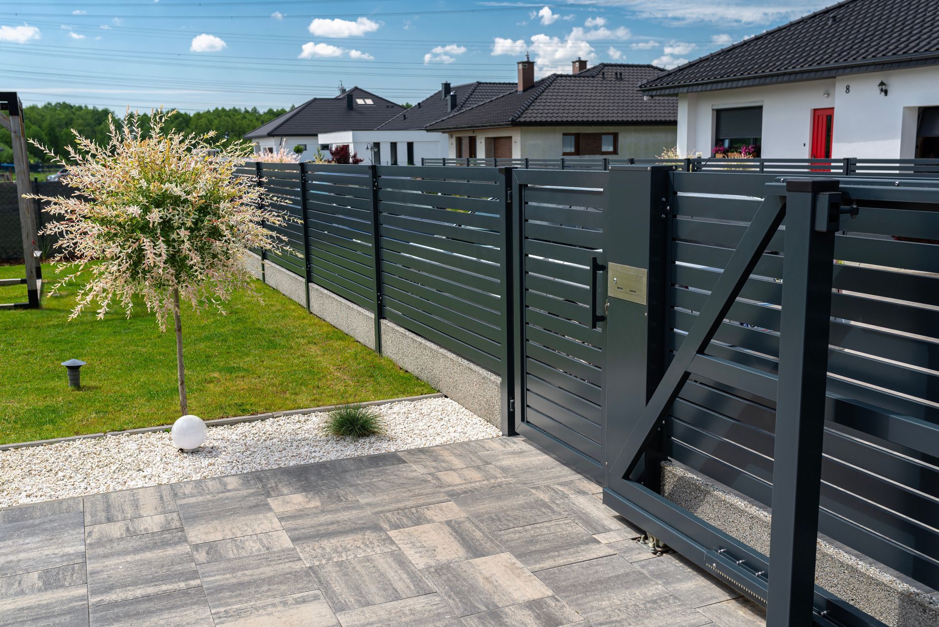A black fence with a sliding gate in front of a house.
