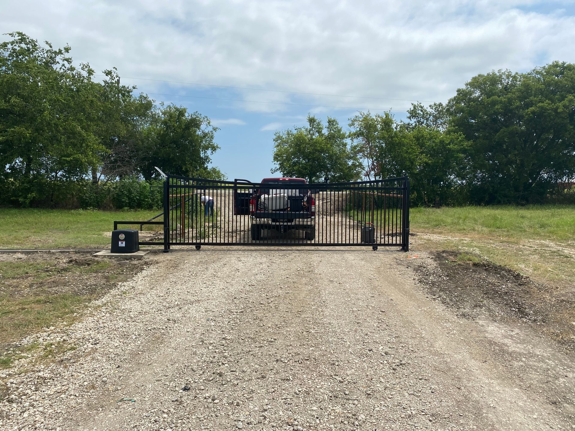 A black fence with a sliding gate in front of a house.